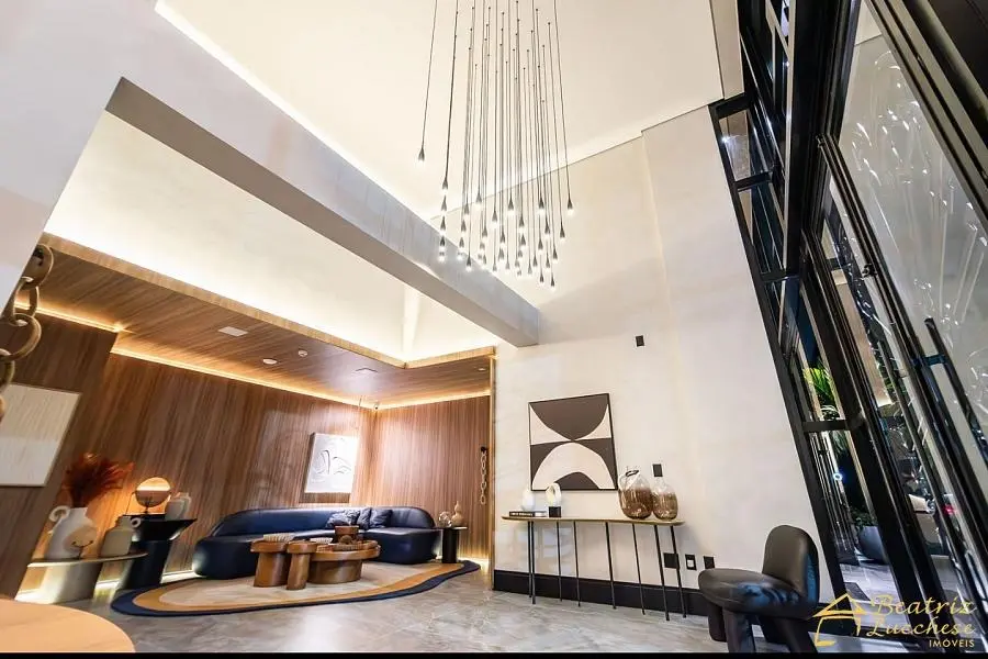 Hall de entrada do Riomaggiore Residenze - Lobby com pé direito duplo, lustre exclusivo e sofá de veludo azul em Balneário Camboriú